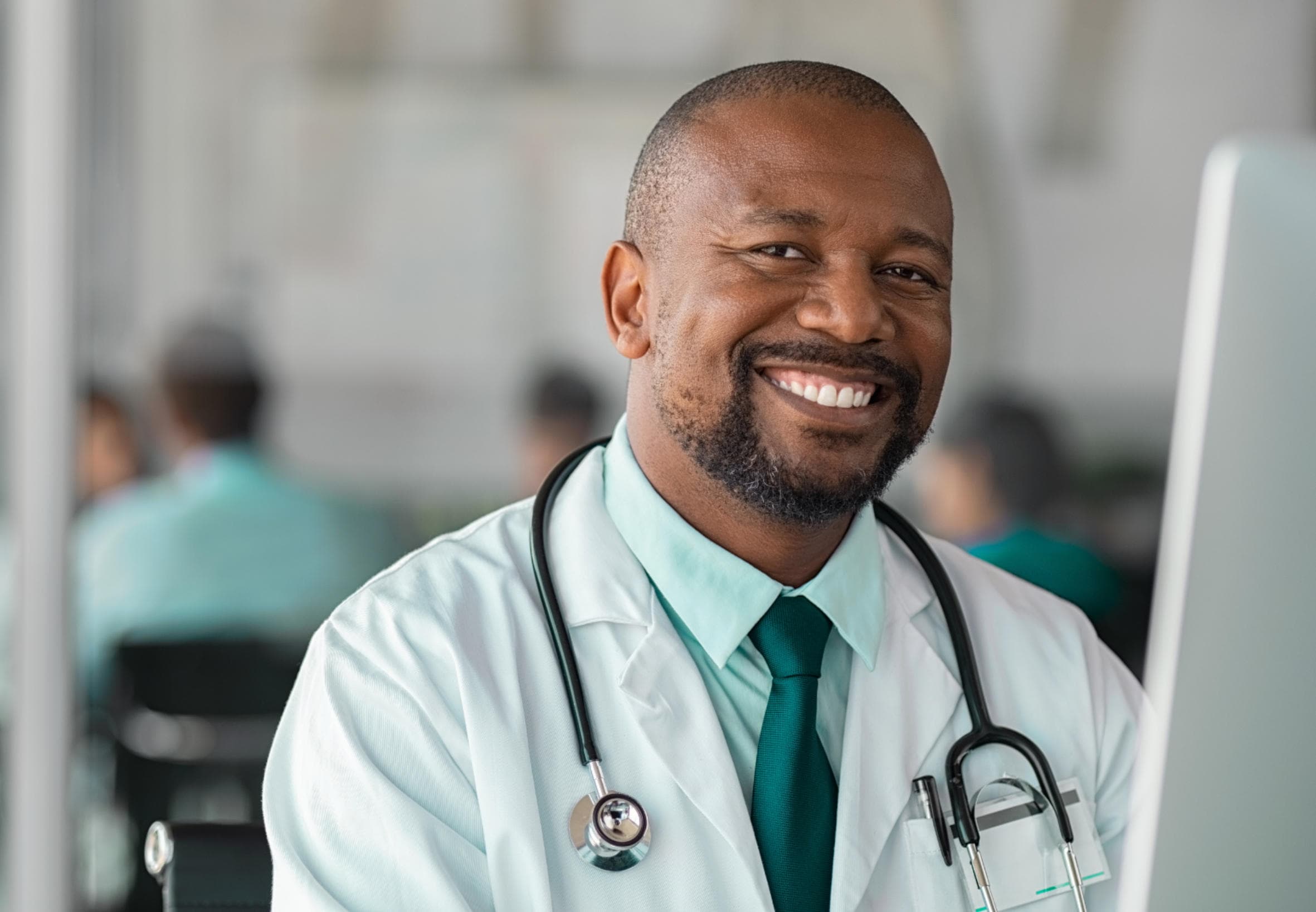 A doctor in a white coat working at a computer.