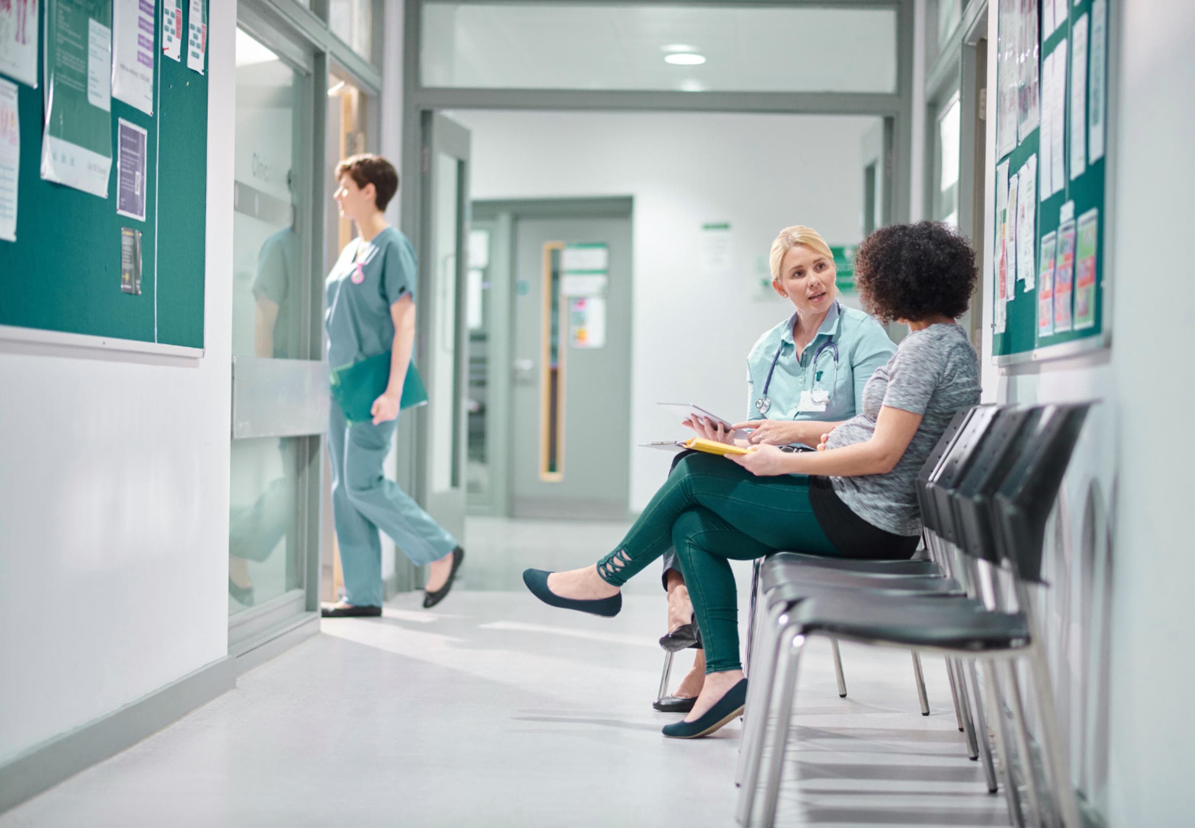 A nurse in a clinic waiting area talking with a patient.
