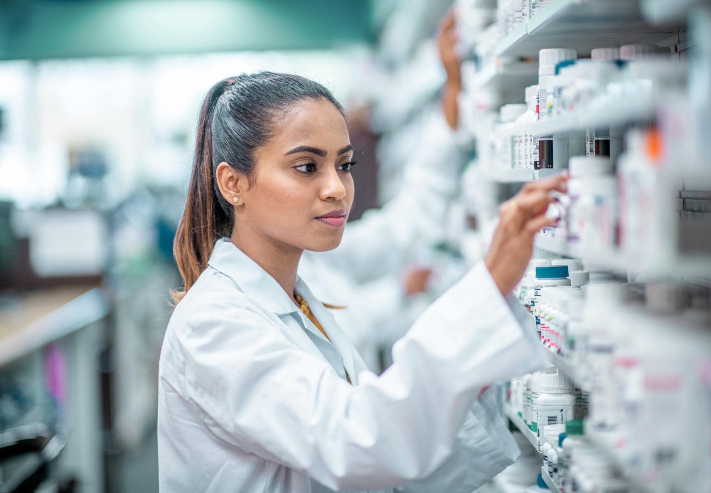 A pharmacist selecting medication from a pharmacy shelf.